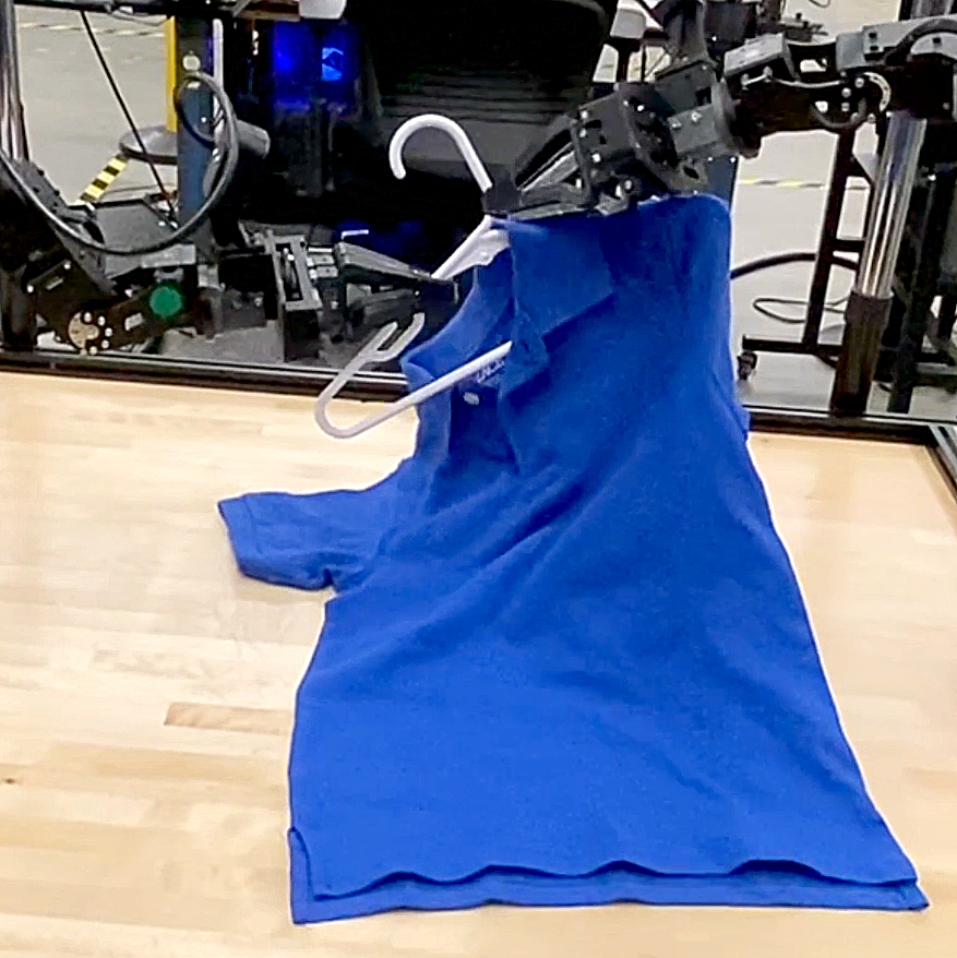 Two robot arms work together to put a blue T-shirt with a collar on a hanger