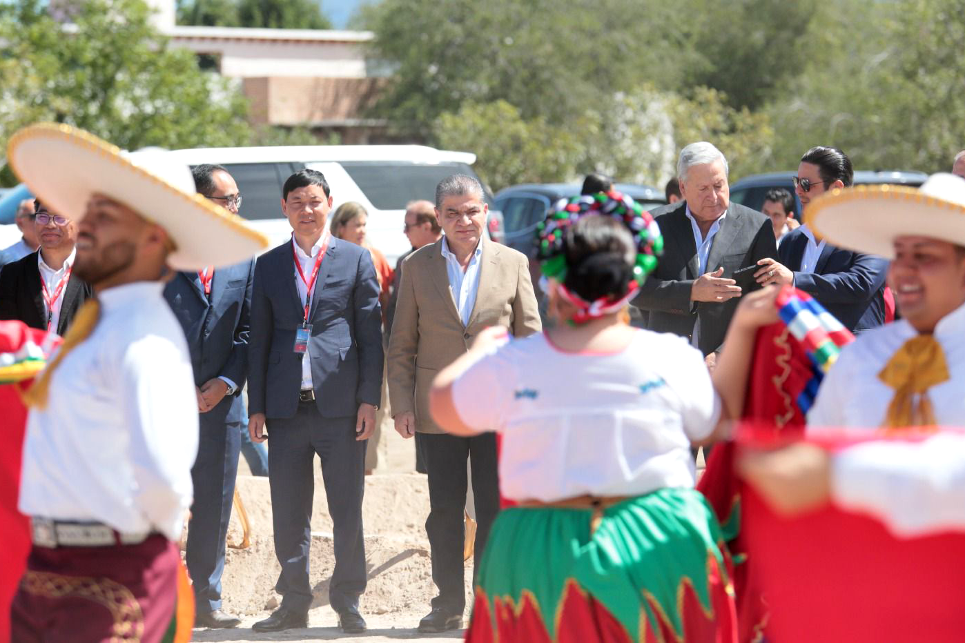 Men in suits look on as dancers in traditional and colorful Mexican clothing put on a show during a groundbreaking ceremony for a Chinese company at Alianza Industrial Park in Coahuila state, Mexico.