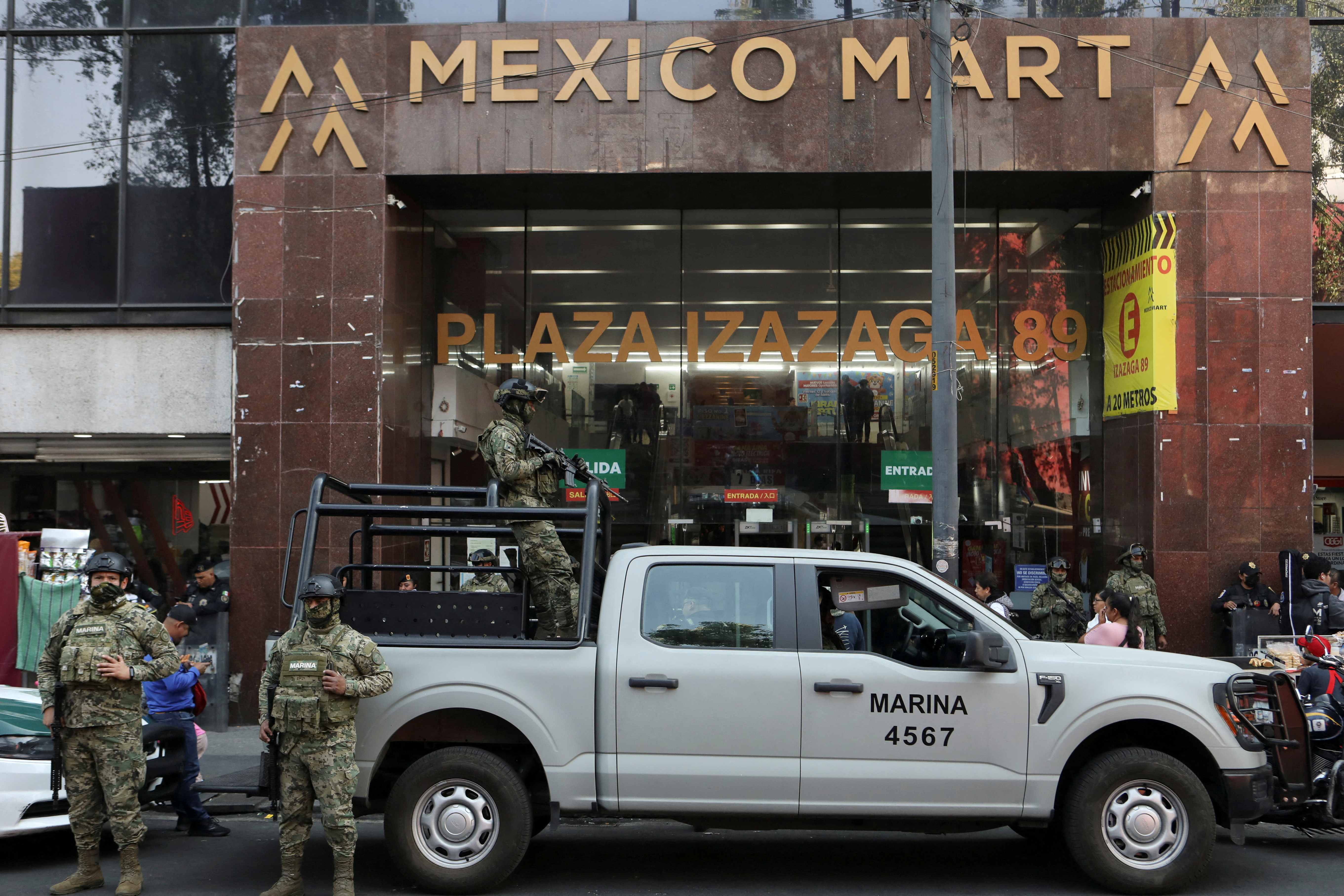 Members of the Mexican Navy in combat gear holding guns stand on top of a pickup truck outside the Mexico Mart shopping mall during an operation by federal authorities in Mexico City to seize Chinese counterfeit goods