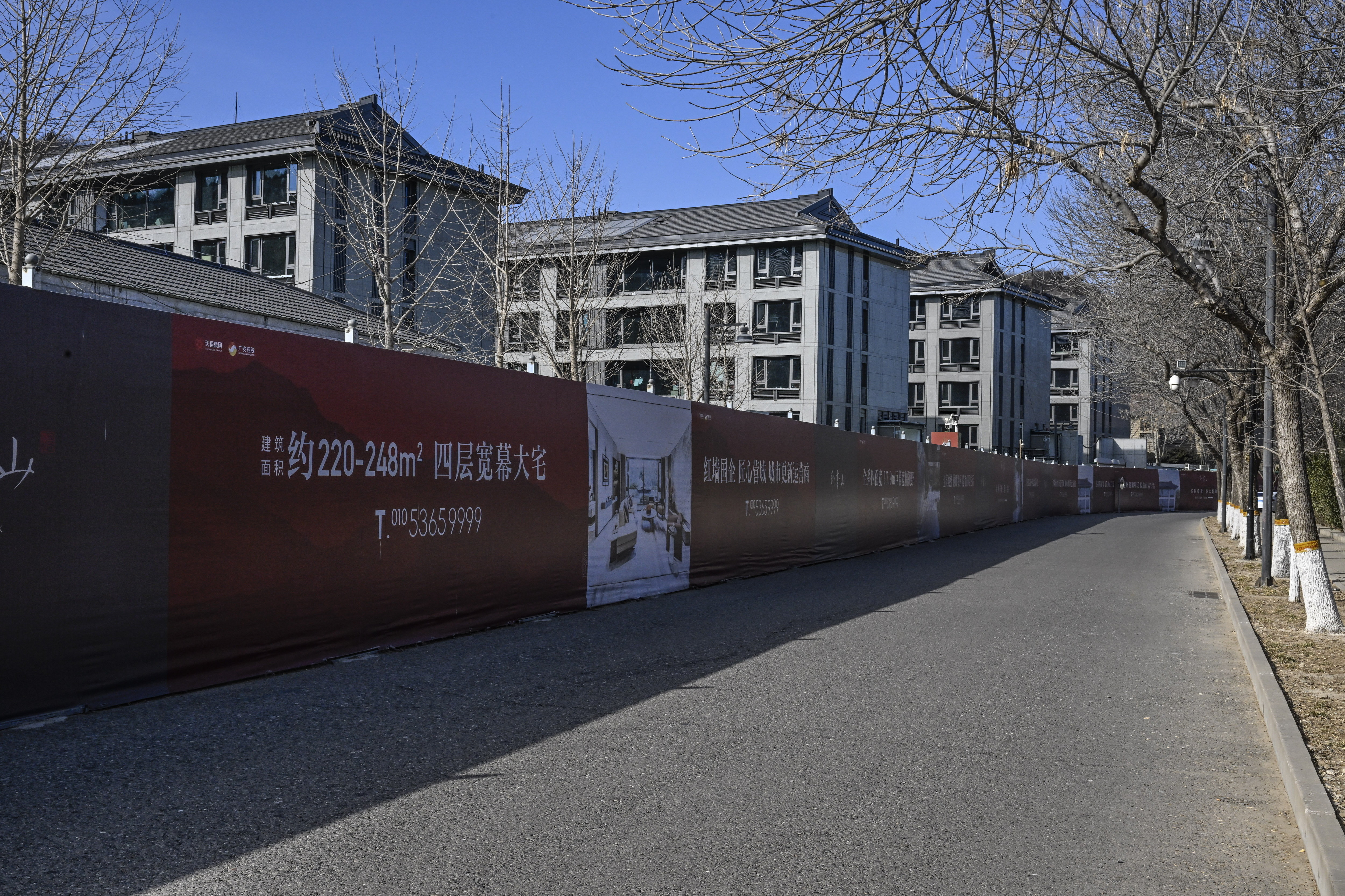 A road runs alongside a different residential complex, partially obscured by a tall red advertisement with Chinese characters and images.