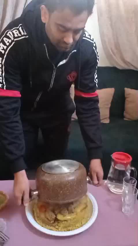 Ramy lifting a pan from the top of a dish of steaming-hot food
