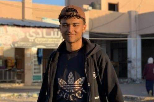 Ramy’s youngest brother Mostafa, smiling to camera wearing a black T-shirt, black hoodie and a backwards baseball cap