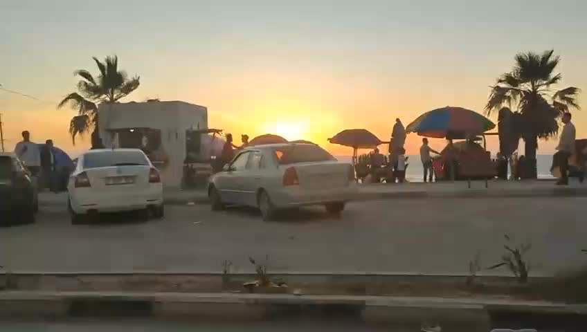 Video footage of Gaza at sunset, with many people walking and driving around