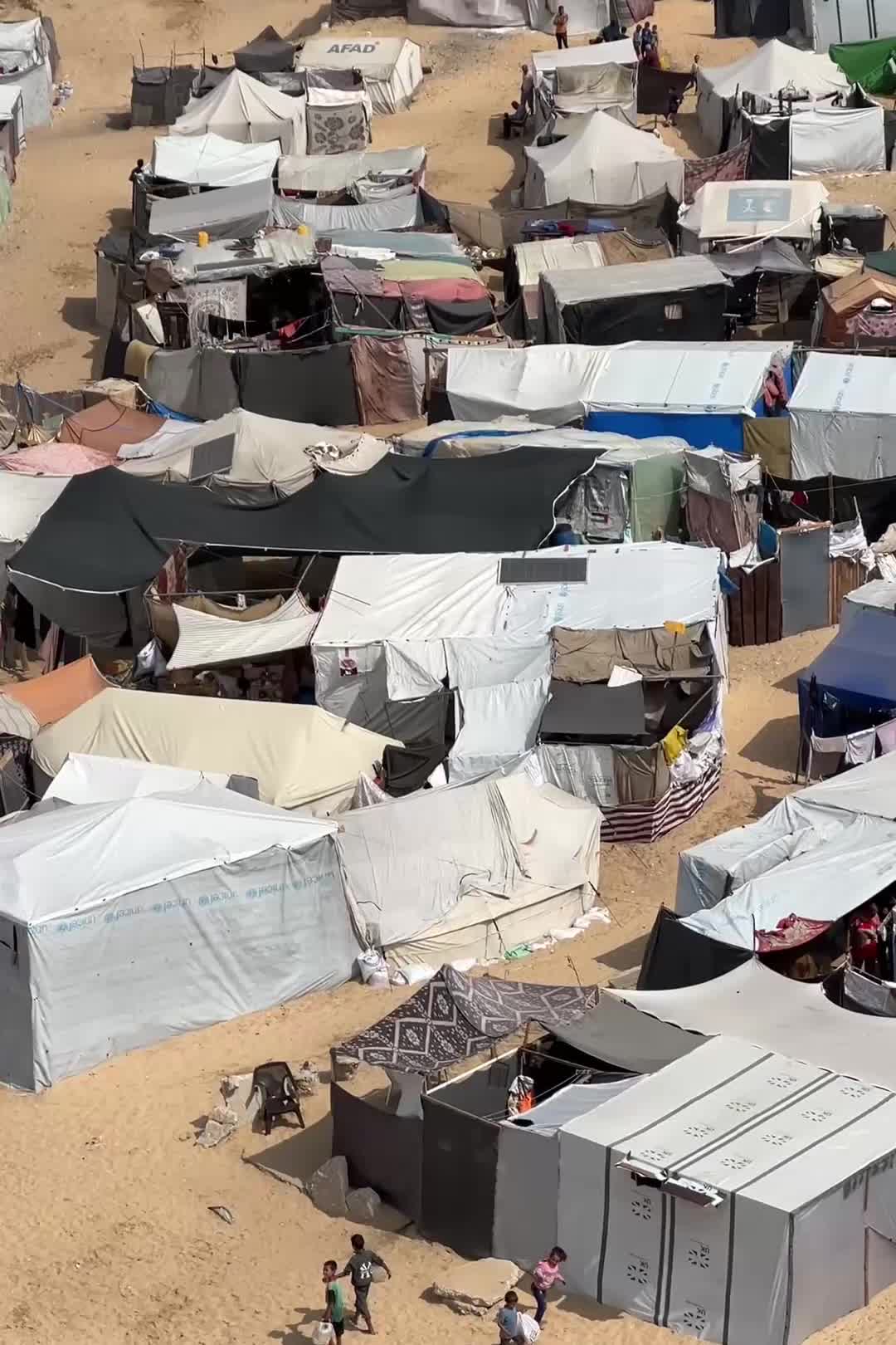 Video footage shows families moving around a sprawling makeshift tented camp