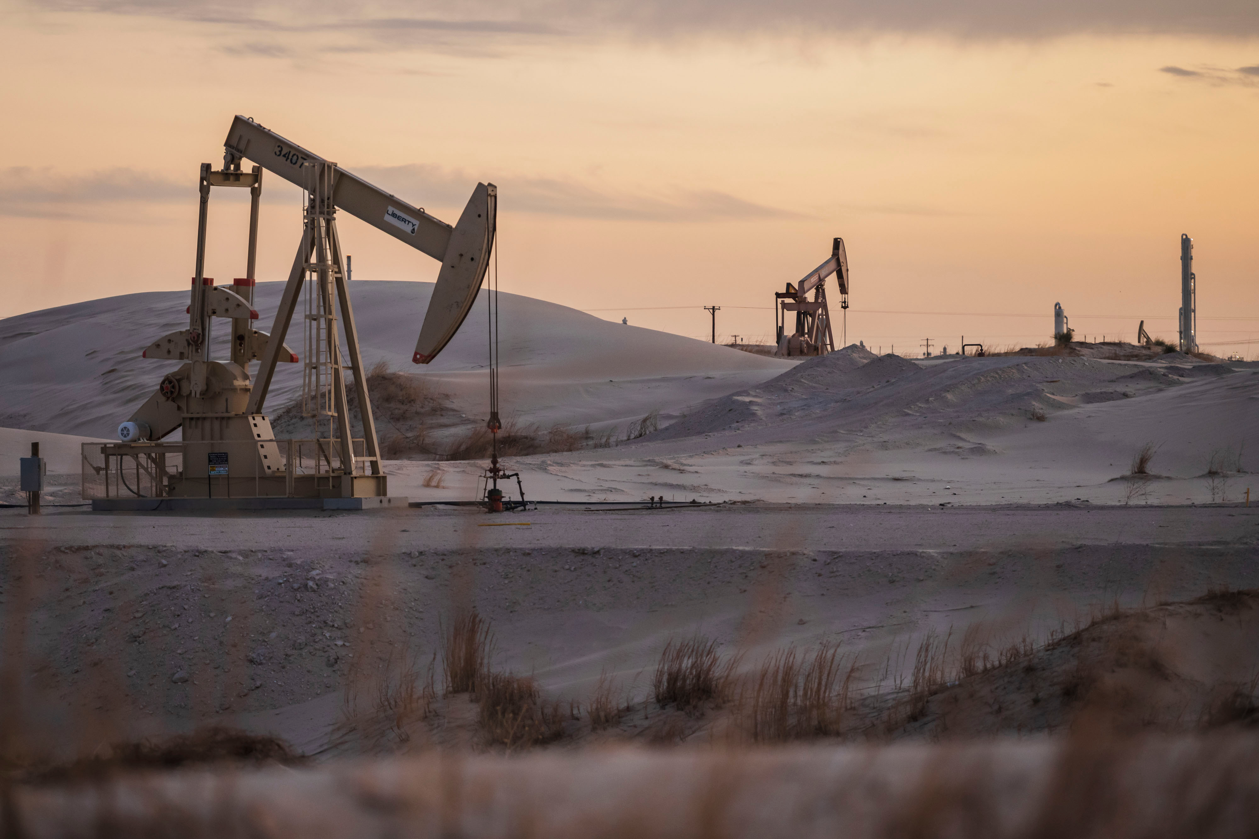Oil pumpjacks operating in a sandy desert landscape in Texas