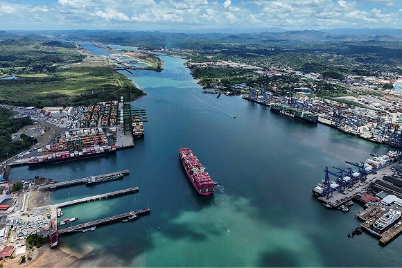 Alt text for image 2: Aerial view of a large cargo ship transiting the Panama Canal — an area lined with ports and containers.