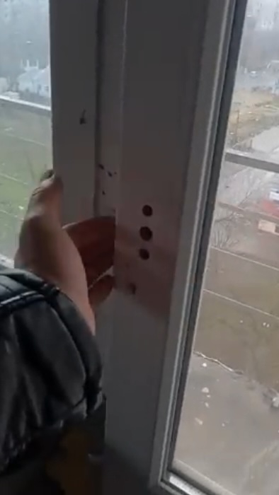 Still image from a video inside an apartment, showing a hand trying to open a window - but it has no handle.