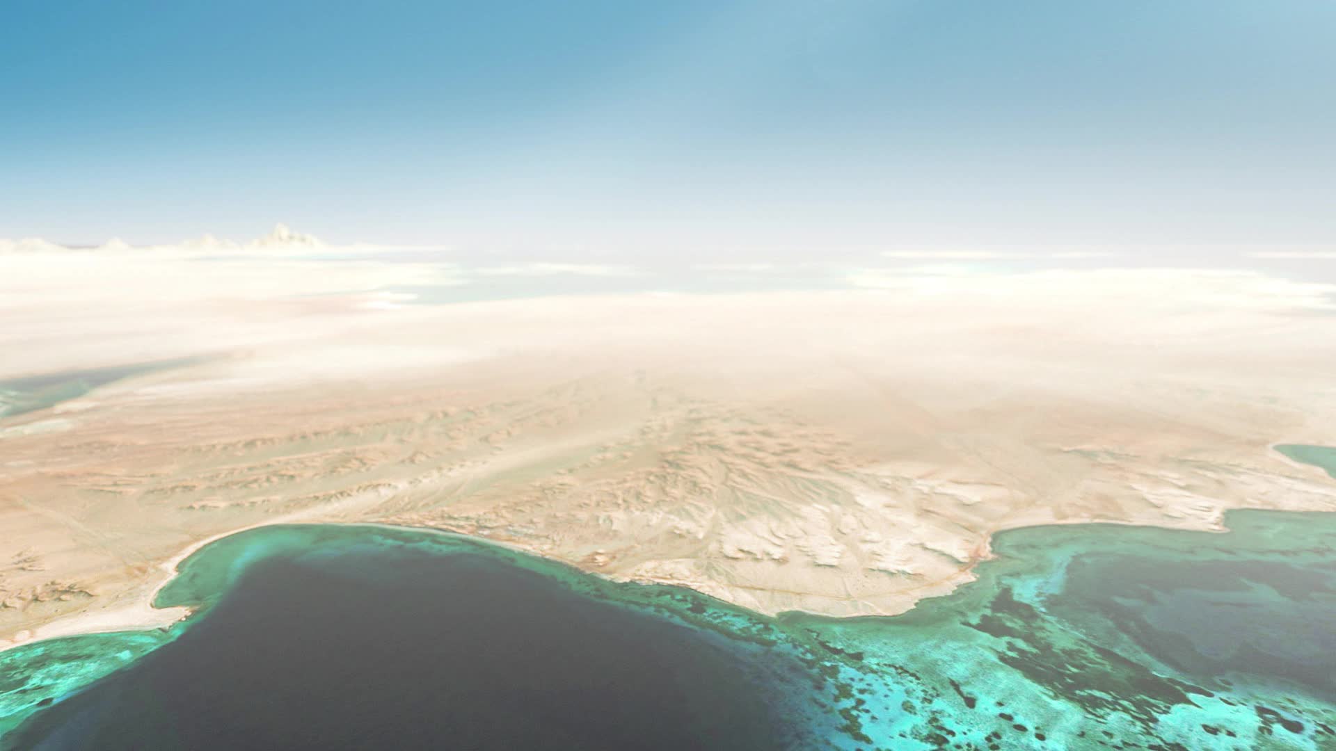 Aerial view of a sandy desert coastline with turquoise coral reefs and a deep blue sea beneath a pale blue sky.