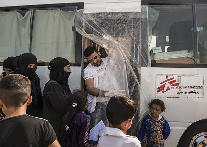 Patients wait outside the MSF mobile clinic to be assessed by the nurse, Sufyan Ahmed, before entering the bus