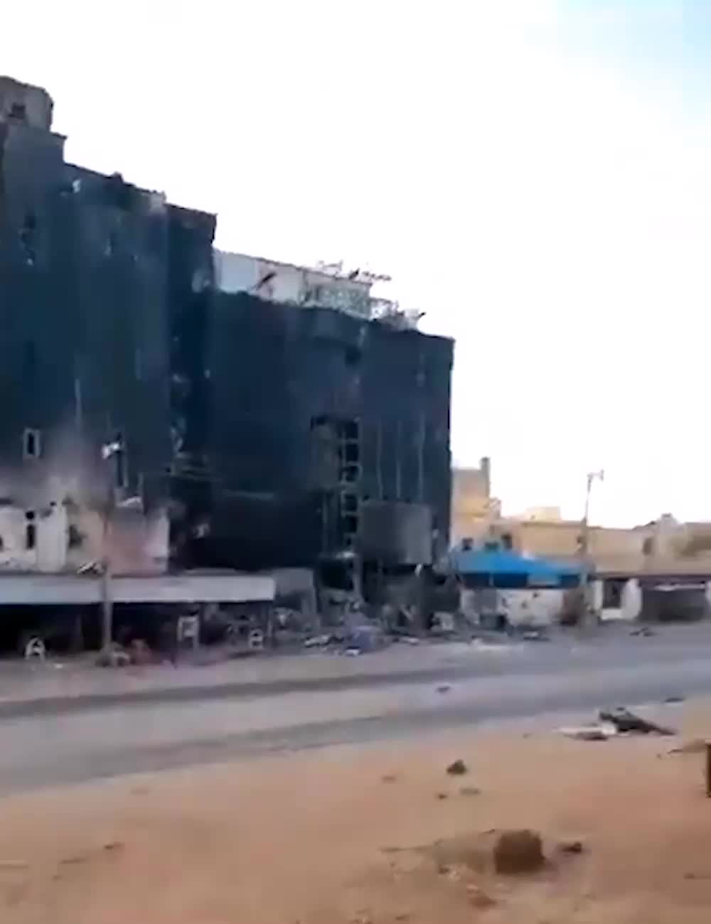 A mobile phone video pans across a large burnt black building