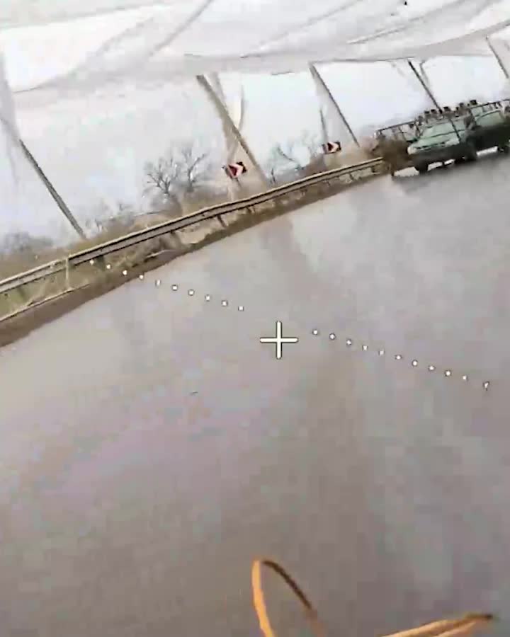 Flooded highway with standing water, a guardrail and parked cars near a curve; a camera crosshair and dotted alignment line are visible.