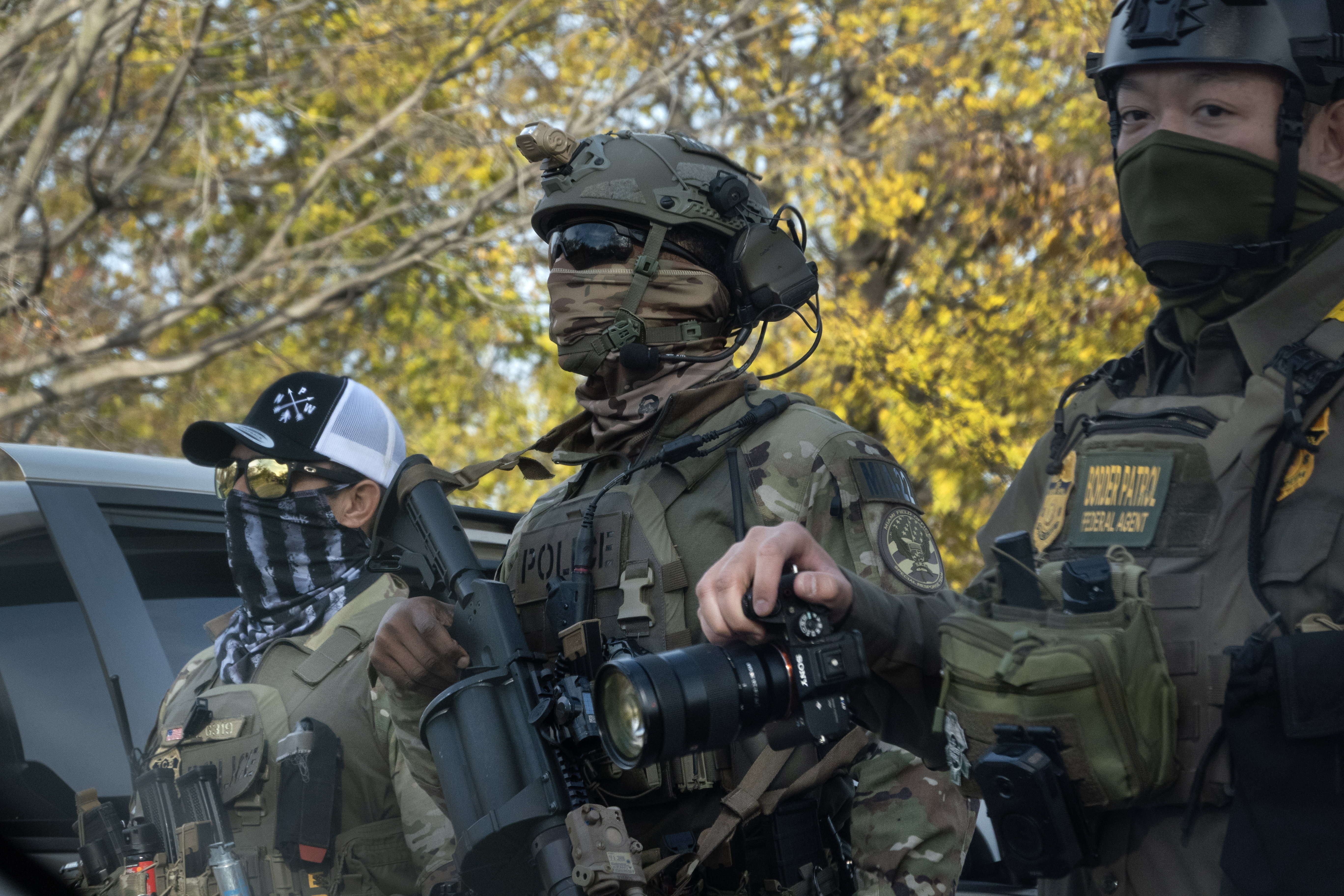 Agents in tactical gear during a search operation are wearing face coverings, helmets and carrying weapons and surveillance equipment.