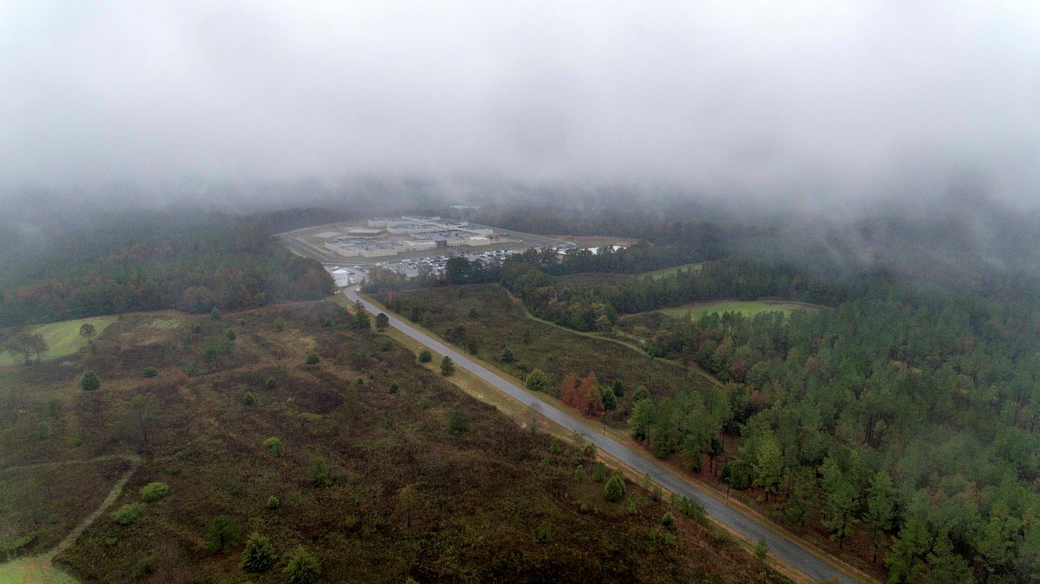 Aerial view of Stewart Detention Center, which is surrounded by dense forest and a misty, overcast sky.